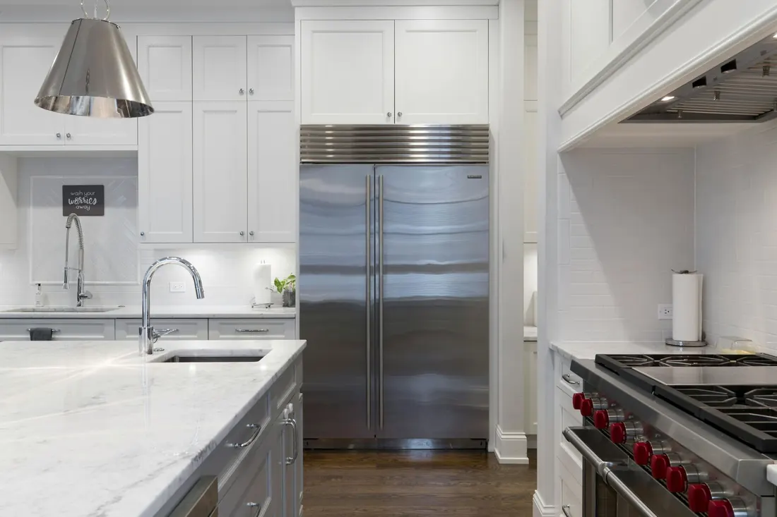 Open dishwasher with an empty, dark gray wire rack, inside a white cabinet.